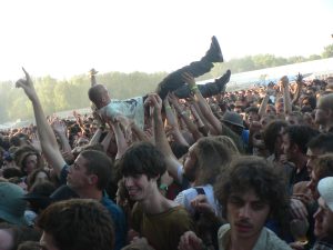An image of a concert crowd, one person crowd surfing, held up by other fans.