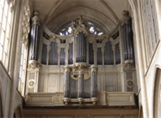 A photograph of the pipes of a large pipe organ that are built into the wall of a church with a vaulted ceiling.