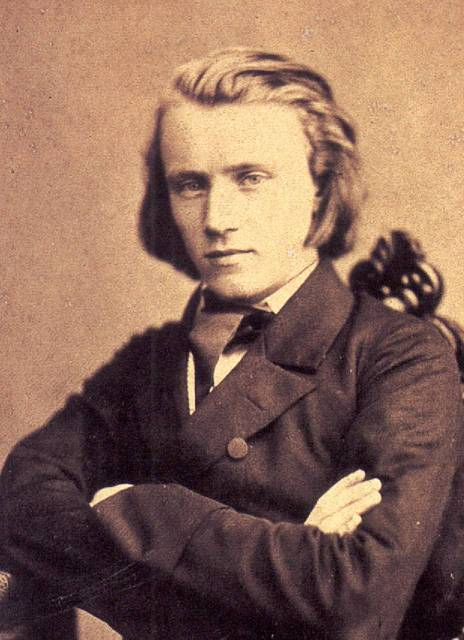 A man with flowing long hair sits in a chair, appearing calm and contemplative.