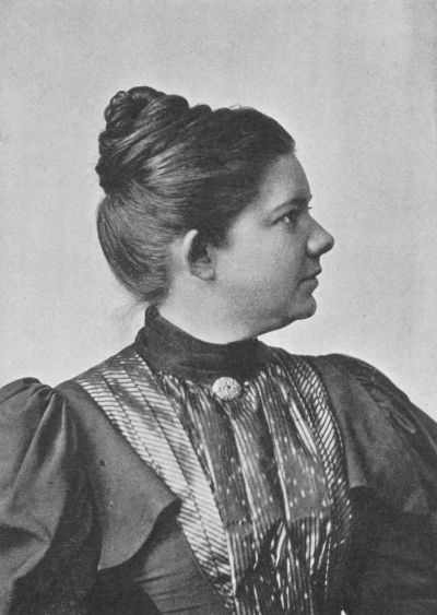 An old black and white photograph depicting a woman elegantly dressed in a vintage gown, exuding timeless charm.