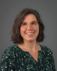 Portrait souriant de Jessica Miller, une femme avec des lunettes et des cheveux châtains mi-longs.